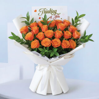 Bouquet of fresh orange roses wrapped in white paper with a ‘Thinking of You’ message card.