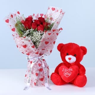 Flower Not Found 9 Bouquet featuring seven red roses styled with gypsophila and lepidium greenery in Valentine heart-print wrapping alongside a red teddy.