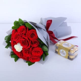 Bouquet of 14 red roses, 1 white rose, ruscus leaves and Ferrero Rocher chocolates in a grey wrap with a red ribbon.