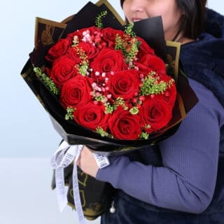 A luxury black-and-gold wrap bouquet featuring red roses, pink baby’s breath and green fillers.