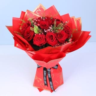 A bouquet of red roses, baby’s breath and green fillers in a red Valentine heart wrapping.