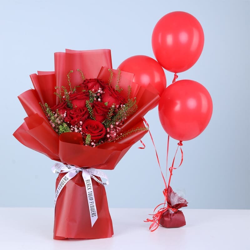 Bouquet of red roses with baby’s breath and green fillers in red wrapping, with three red balloons.