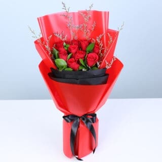 Red roses bouquet with greenery in bold red and black wrapping.