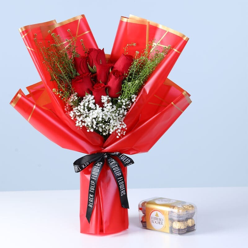 red-roses-peach-wrap-16-ferrero-rocher-box_2026 25 red roses bouquet with white filler flowers and green foliage in pink wrapping, with a mini Ferrero chocolate pack.
