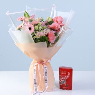 BTF Home 53 Bouquet of pink roses, gerberas, lilies, and seasonal blooms in soft peach wrapping, finished with a ribbon bow and paired with a Lindt Lindor chocolate box.