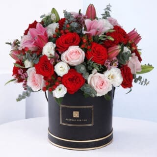 A lush mix of vibrant flowers arranged in a decorative black flower box, designed as a stylish floral gift arrangement.