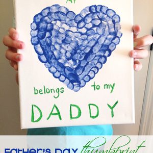 a piece of artwork created for Father's Day. The artwork is on a white canvas and features a heart shape made from blue thumbprints.