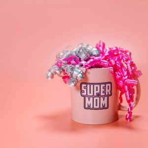 personalized Mothers dau mug a light pink ceramic mug with the words "SUPER MOM" printed on the side in a bold, outlined font.